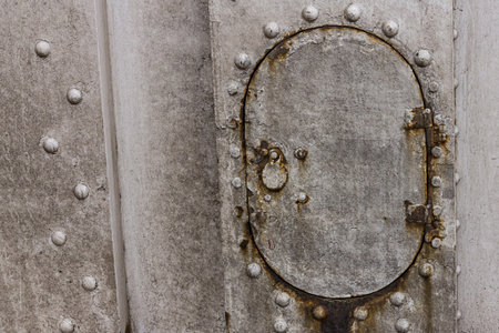 iron hatch oval technical hole on  background gray surface rivets weather-beaten rusty base industrial designの写真素材