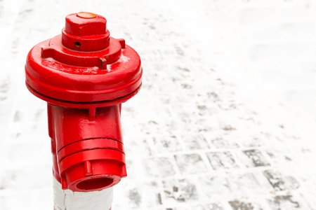 industrial background red hydrant close-up contrasting on a background of snow stone area copy spaceの写真素材