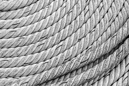 thick rope gray braided weathered old folded in a circle piece parallel lines rigid base marine designの写真素材