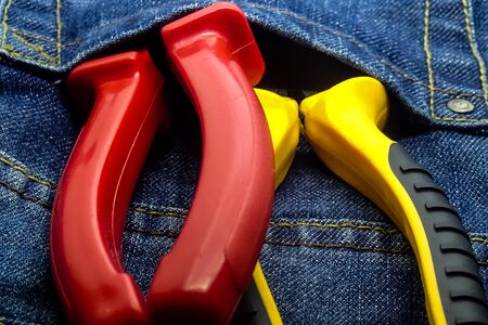 pair screwdrivers plastic pliers pliers vertically in the pocket of the building overallsの写真素材