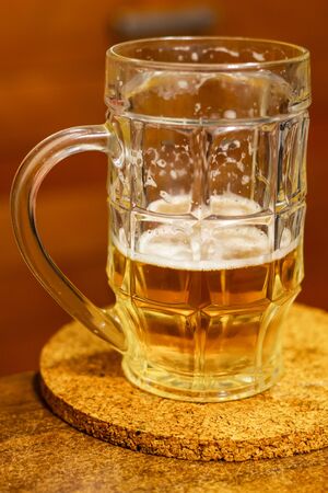 mug beer half on a wooden stand on a blurred background holiday holiday drink hopの写真素材
