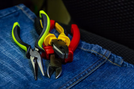 bunch of pliers with plastic yellow and black handles lies on a blue background a work tool