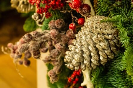 festive decor decorated with a big pine cone and holly red berries decorates a fir tree close-upの写真素材