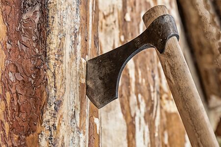 Vintage ax with a narrow blade stuck in a vertical wooden panel close-upの写真素材