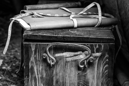 wooden box with forged metal handles and a leather folder lies on top in gray tinted colorsの写真素材