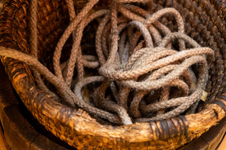 thin natural beige rope lies in a deep wooden basket close-up