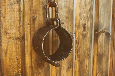 brown iron shackles medieval handcuffs hold slaves close-up vintage on wooden backgroundの写真素材