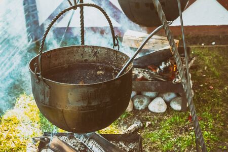 old iron cauldron large burning wood cooking food stained backgroundの写真素材