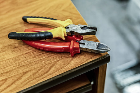pair pliers bright handles red yellow on a wooden table working engineer