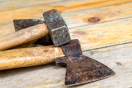 old ax hammer heavy black shabby lies on a wooden background construction tool