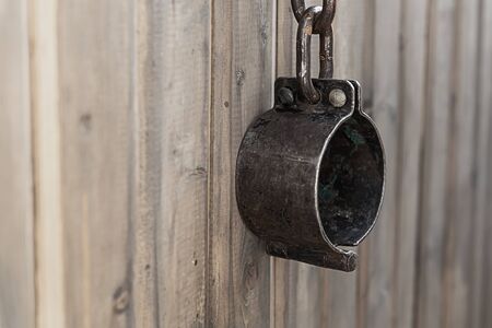 old rusty and forged shackles closeup hanging on a wooden wallの写真素材