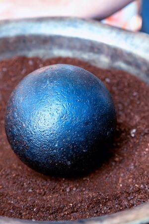 cannonball black and round close-up lies on a dark brown backgroundの写真素材