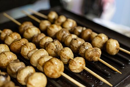 marinated mushrooms strung on wooden skewers cooked on the grillの写真素材