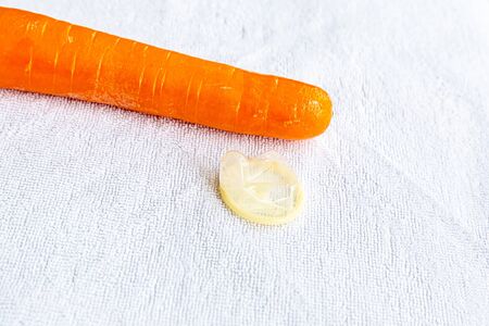 safe sex symbol, set carrots and condom close-up lies on a white backgroundの写真素材