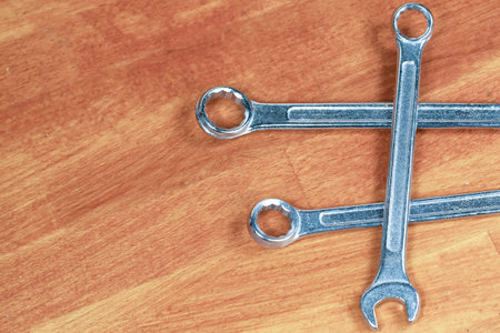 chromed iron wrench, work tool set lies on a wooden table close-up