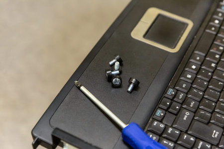 laptop keyboard with touchscreen repair equipment, on the surface lies a screw and screwdriver