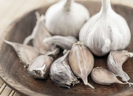 cloves of garlic not peeled on a background whole closeup on a wooden plateの写真素材