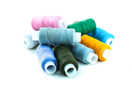 spools of thread for sewing multi-colored blue and green on a white background isolated