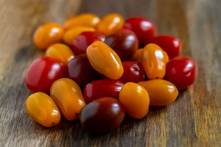 assorted cherry tomato kumquat and yellow on a wooden background close-upの写真素材