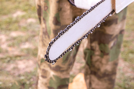 chainsaw close up on blurred background camouflage gardener