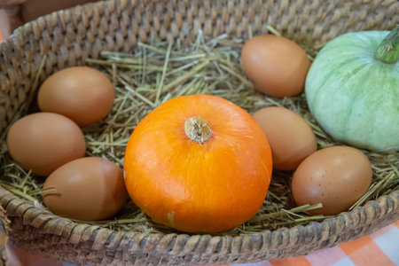 orange pumpkin and eggs in a wicker plate selective focusの写真素材