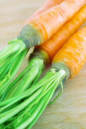 orange carrot with green tops close-up on wooden backgroundの写真素材