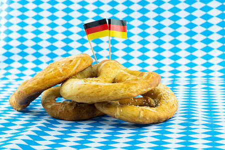 stack of pretzels and germany flag on blue and white background oktoberfest symbolの写真素材