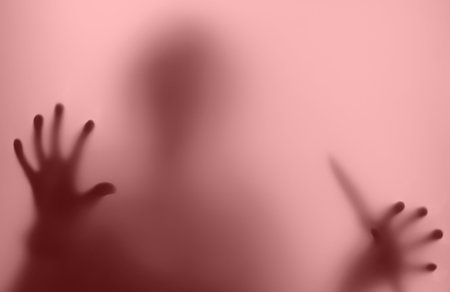 silhouette in a red haze blurred, stands with a knife in the window - in a nightmareの写真素材