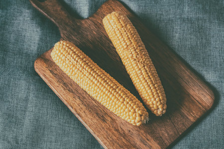 corn a couple of cobs on a wooden cutting board toned backgroundの写真素材
