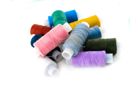 pile of thread of bright thread and gray material for embroidery of pictures and darnings on a white...