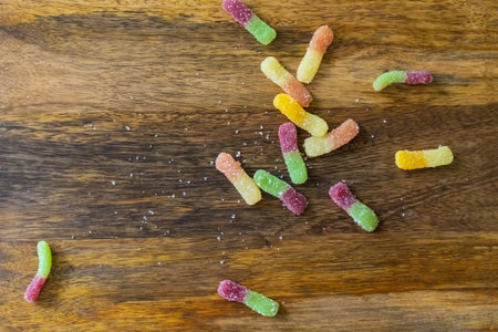 gummy candies scattered on a wooden background, multi-colored gummiesの写真素材