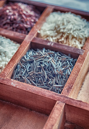 wooden box with four sections filled with rice red and black close-upの写真素材