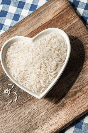 long white rice in a shaped plate in the shape of a heart on a wooden backgroundの写真素材