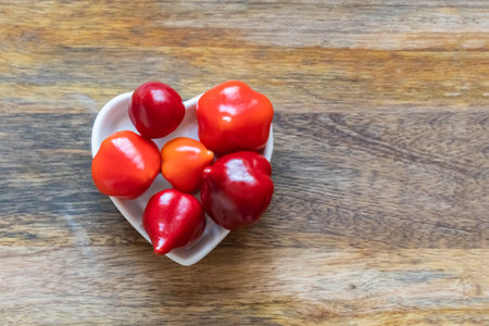 assorted red chili peppers and spicy mini stacked in a plate heart top viewの写真素材