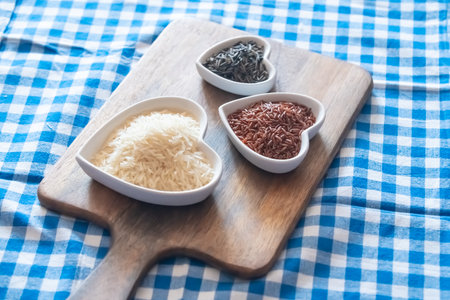 red, white and black rice on a wooden cutting board and checkered tableclothの写真素材