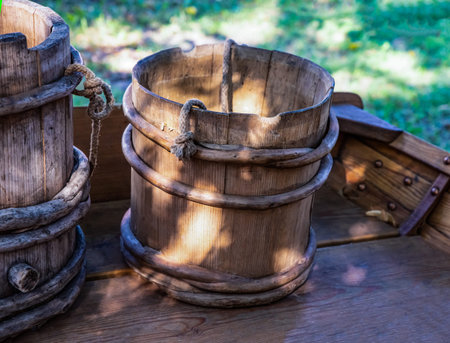 old and weathered wooden bucket stands in the shadeの写真素材