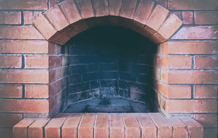 red brick fireplace with open hearth close-up, traditional heating methodの写真素材