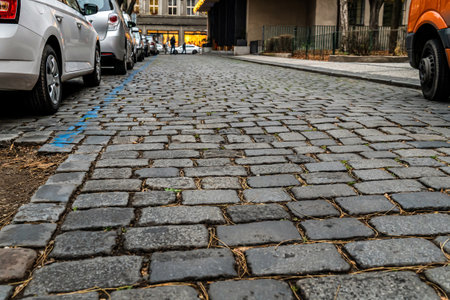 stone road from gray cobblestones, city street with cars, low angle photoの写真素材