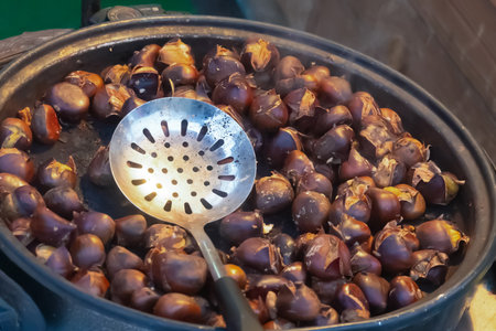 fire-roasted chestnuts folded in a pan for cooking over a fireの写真素材