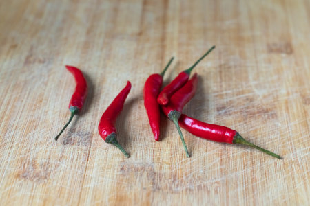 several fresh red chili peppers on a wooden surfaceの写真素材
