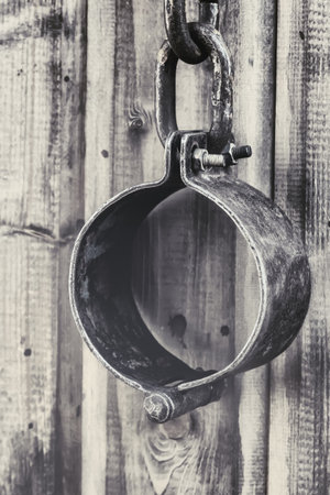 old and rusty shackles closed traditional design handcuffs hanging on a wall backgroundの写真素材