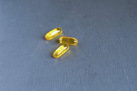 3 yellow tablets vitamins omega 3 6 9 in capsule form lie on a neutral backgroundの写真素材