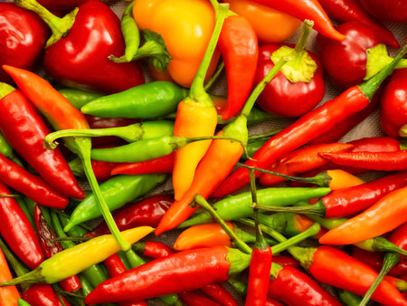 A bunch of red peppers and yellow peppers are piled on top of each other.