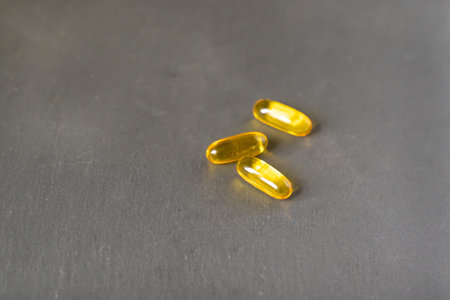 yellow tablets vitamins omega 3 6 9 in capsule form lie on a neutral backgroundの写真素材