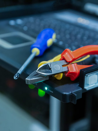 A pair of pliers and a screwdriver are on a laptop