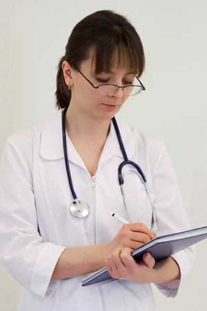 physician in spectacles writing with penの写真素材