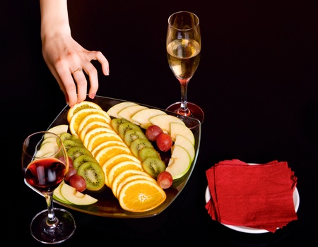 fruit with wine glasses and hand on black tableの写真素材