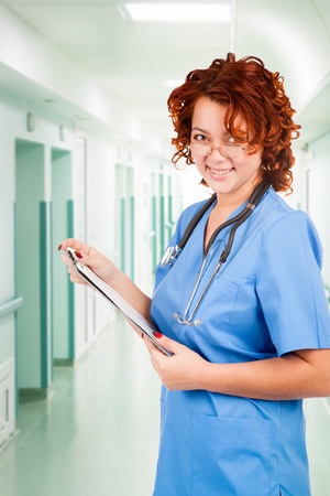 young smiley female doctor with stethoscope in clinic's corridorの写真素材