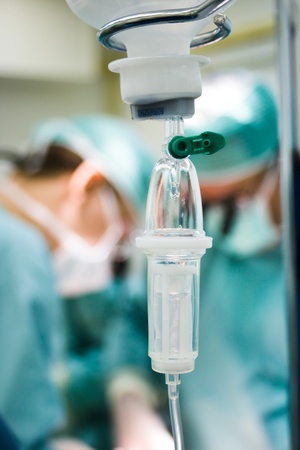 intravenous drip in operation room with surgeons on backgroundの写真素材