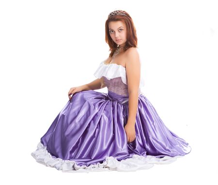 young attractive sitting woman in long lilac-coloured ball dress and with diadem on head women isolated on white backgroundの写真素材